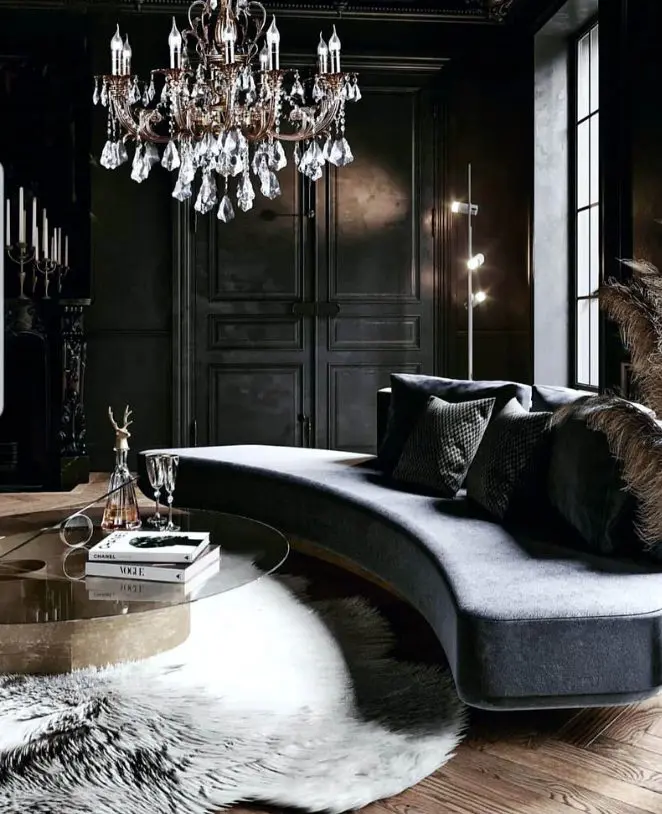 a gorgeous refined living room in goth style, with soot walls, a grey curved sofa, a crystal chandelier and a glass table