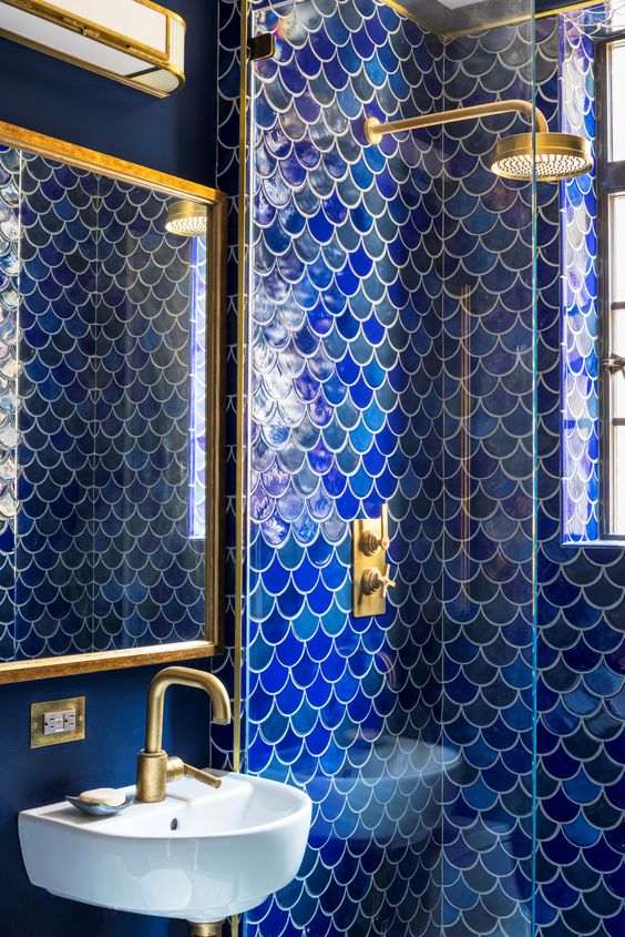 a jaw-dropping bold blue and navy bathroom with fish scale tile in the shower and brushed gold fixtures is wow