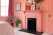 a lively Peach Fuzz bedroom with a fireplace, a bed, a rattan chair, some potted plants and decor