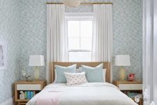 a lovely and peaceful teen bedroom with blue wallpaper, a stained bed with pastel bedding, stained nightstands, pendant lamps