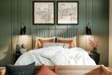 a lovely boho meets modern earthy bedroom with grene paneling, a bed with neutral bedding, a bench with pillows and sconces