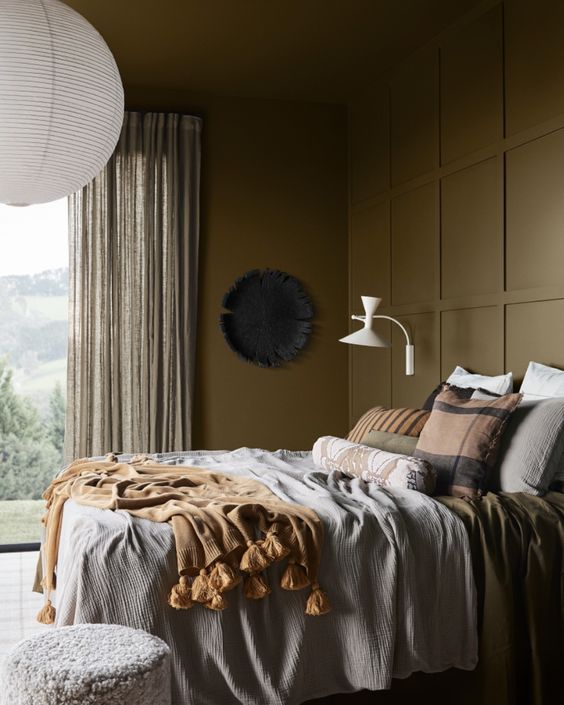 a lovely earthy bedroom with brown walls, a bed with earthy bedding, some lamps and a cool view of outdoors