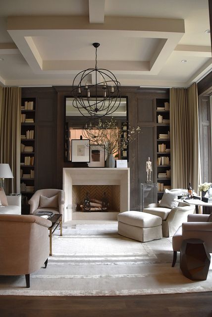 A lovely living room with taupe walls, built in shelves, a fireplace, neutral seating furniture and a sphere lamp