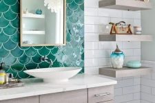 a lovely seaside bathroom done with white subway and emerald fishscale tiles, a stained vanity and open shelves, a wall lamp