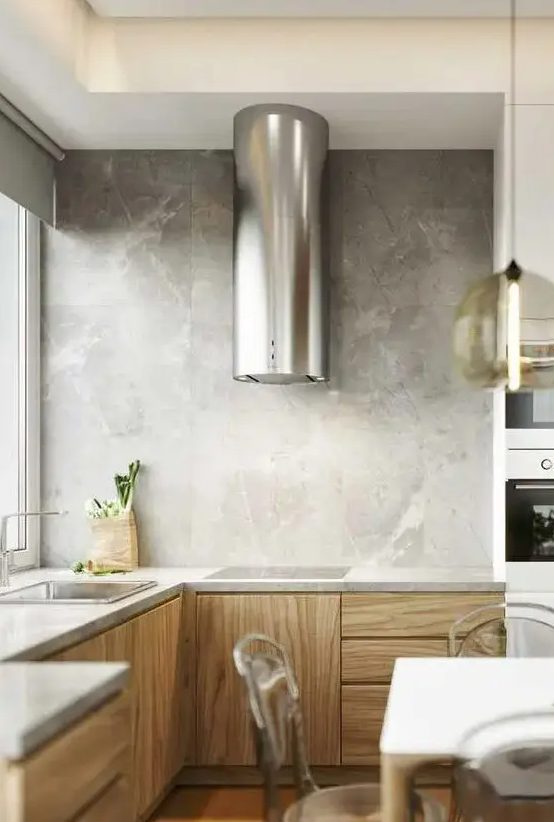 a minimalist stained kitchen with stone countertops and a backsplash and a statement metallic hood over the cooking top