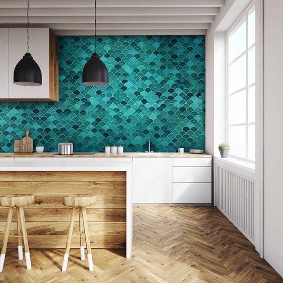 a minimalist white kitchen with butcherblock countertops, a super bold green scallop tile backsplash and black lamps