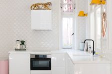 a minimalist white kitchen with glossy cabinets, white stone countertops, white scallop tile walls, yellow lamps and pink touches