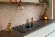 a minimalist white kitchen with sleek cabinets, an open shelf, a blush scallop tile backsplash and dark stone countertops