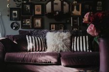 a modern Goth living room with grey walls, a purple sofa and striped pillows, a spectacular gallery wall