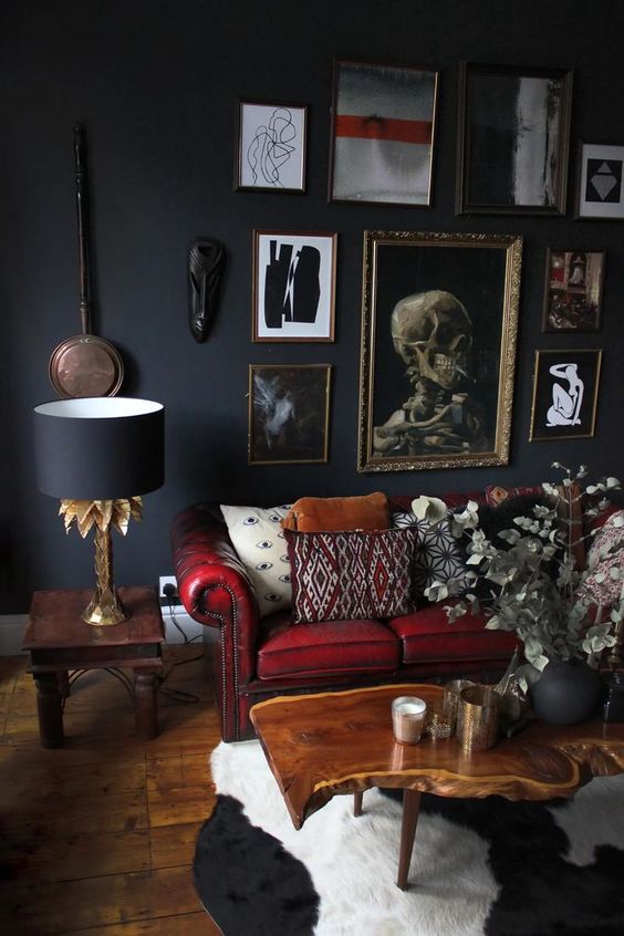 a modern Goth living room with soot walls, a red sofa and colorful pillows, a gallery wall, a living edge table and dried blooms