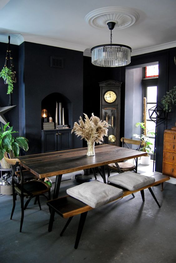 A modern Gothic dining space with a built in cabinet, a stained dining set, potted plants, a grandfather's clock