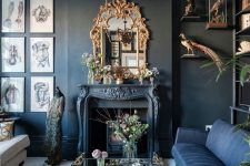 a modern Gothic living room with black walls, a blue and white sofa, a fireplace, a refined chandelier and mirror, catchy artworks