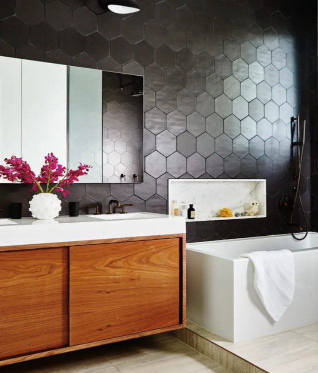 a modern bathroom with soot hexagon tiles, neutral tiles, a rich stained vanity, a tub and a mirror cabinet