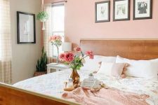 a modern bedroom with a Peach Fuzz accent wall, a stained bed with printed bedding, a nightstand, a tassel chandelier and some blooms
