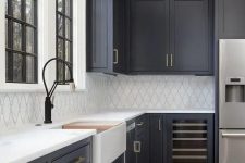 a modern farmhouse kitchen with soot cabinets, a white tile backsplash and white stone countertops, brass handles