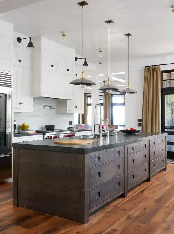 A modern kitchen with white cabinets, a white subway tile backsplash, a dark stained kitchen island and pendant lamps