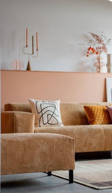 a modern living room with a Peach Fuzz built-in shelf, a beige corduroy sofa and pillows and some decor