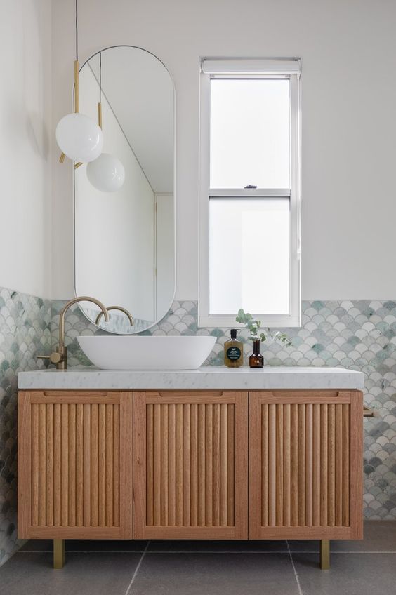 a modern sink space done with mermaid inspired fish scale tiles, a fluted vanity, a sink, a cool pendant lamp