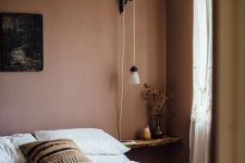 a moody and earthy guest bedroom with a bed and earthy bedding, a living edge nightstand and a pendant lamp
