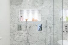 a neutral bathroom done with marble fish scale tiles, a shower and a tub, white appliances and built-in lights