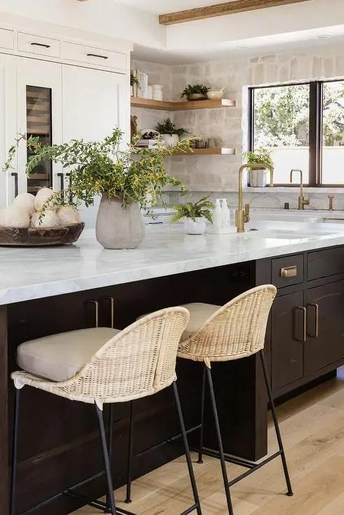 A neutral kitchen with white shaker cabinets, a stone backsplash and open shelves, a dark stained kitchen island with a stone countertop