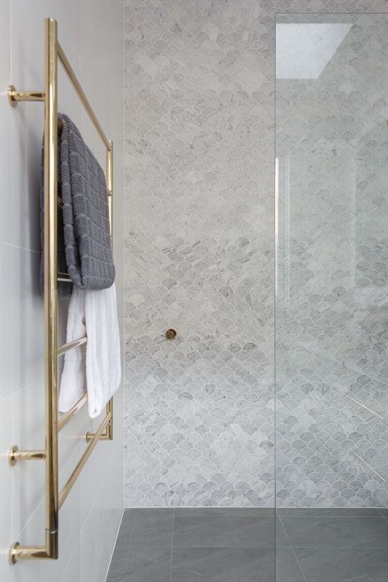 a neutral shower space with grey marble fish scale tiles, a gold radiator is a cool and stylish modern space