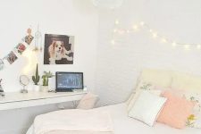 a neutral teen bedroom with a floating desk and vanity, a bed with pastel pillows and lights on the wall