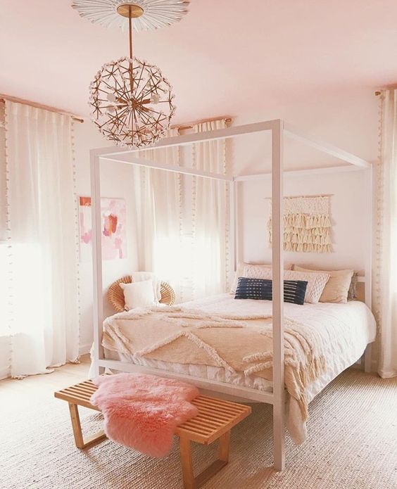 a neutral teen bedroom with a neutral bed and bedding, a stained bench with peachy faux fur and a floral chandelier