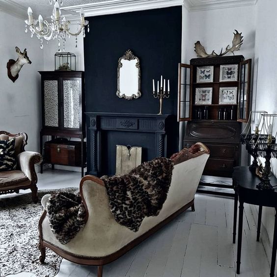 a non-traditional Gothic living room with a fireplace, refined vintage seating furniture, dark-stained storage units and a crystal chandelier