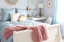a pastel bedroom with a white bed and pastel bedding, blue curtains, a white desk as a nightstand, a white chair, a clock, a mirror and a table lamp