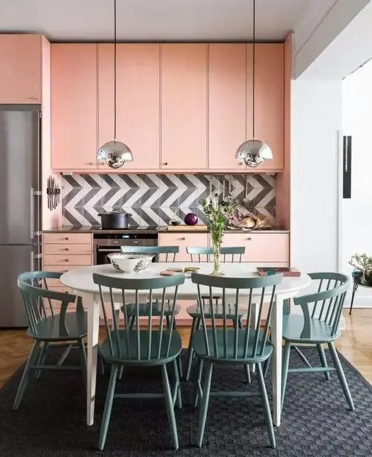 A peachy pink mid century modern kitchen with a graphic tile backsplash and a dining zone in blue right here