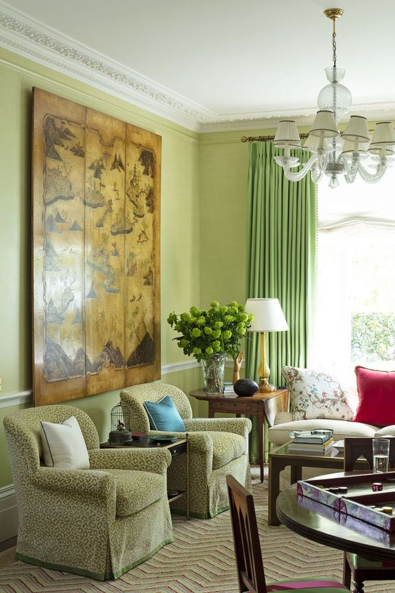 a refined chartreuse living room with green chairs, a white sofa with pillows, an oversized artwork, elegant tables