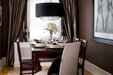 a refined dining space with brown walls, dark-stained furniture, art and lamps and candles is amazing