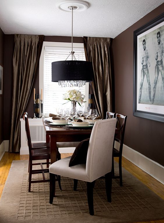 a refined dining space with brown walls, dark-stained furniture, art and lamps and candles is amazing