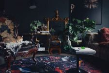 a refined modern Goth living room with soot walls and a ceiling, vintage seating furniture, a bold rug and blankets and potted plants