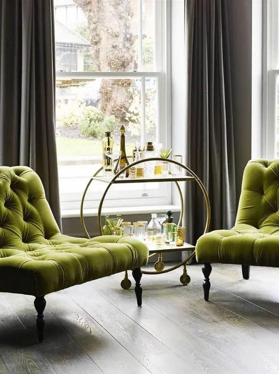 a refined nook with elegant chartreuse tufted chairs, a chic bar cart and grey curtains is a cool space