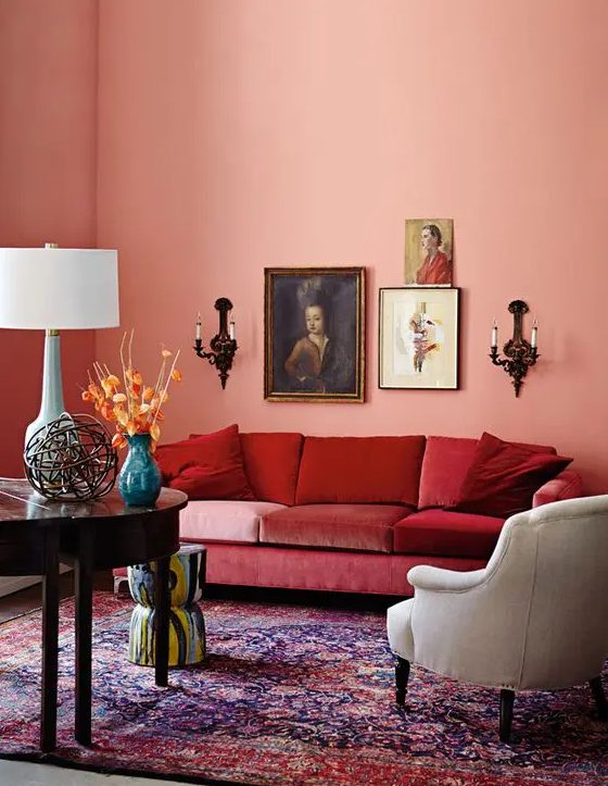 a refined vintage Peach Fuzz living room with a red sofa, a white chair, a colorful rug, a small gallery wall