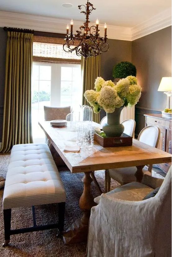 a refined vintage dining room with taupe walls, a vintage stained table, neutral chairs and an upholstered bench, a chic chandelier