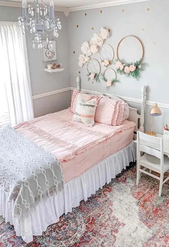 a romantic vintage teen bedroom with light blue walls, vintage neutral furniture, wreaths with blooms, a blue crystal chandelier and pastel bedding