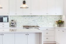 a serene white kitchen with shaker cabinets, a light grey, aqua and green fish scale tile backsplash and white countertops