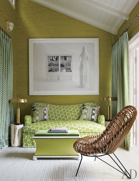 a small attic chartreuse living room with a printed sofa, an ottoman, a rattan chair and green printed curtains