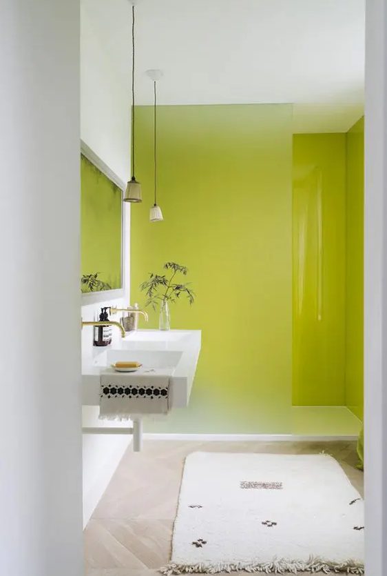 a small yet bold bathroom with chartreuse walls in the shower, an iced glass divider, a floating sink, a neutral rug and pendant lamps