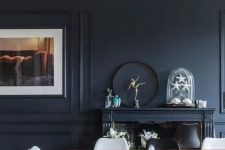 a soot dining room with a fireplace, a stained dining table, black and white chairs, an artwork and some decor