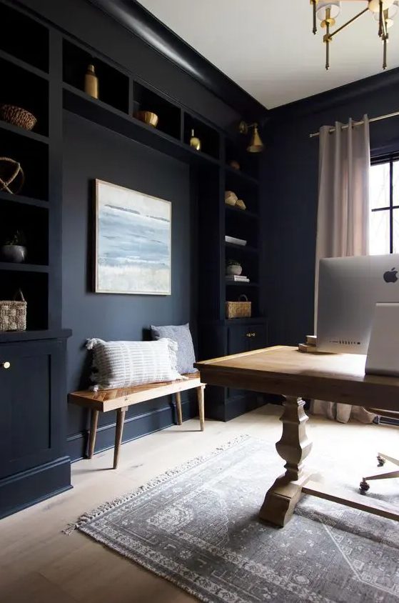 a soot home office with built-in cabinets and shelves, a light-stained vintage table, a bench and a printed rug