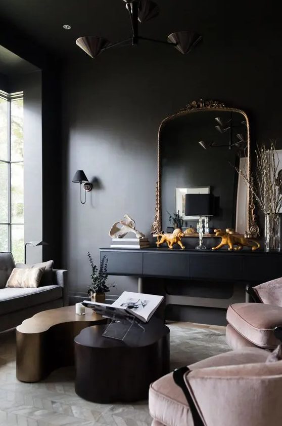 a soot living room with a black console and a chic mirror, blush chairs, a grey sofa, eye catching coffee tables