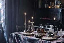 a sophisticated dining room with black walls, a black piano, vintage chairs, an emerald bench, candles and floral linens