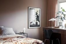 a stylish modern brown bedroom with a bed and printed bedding, a dark-stained desk and a black chair