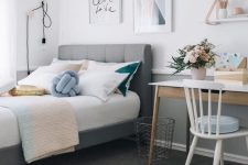 a stylish modern teen girl bedroom with a gallery wall, a grey upholstered bed, a small desk and touches of powder blue, blush and gold