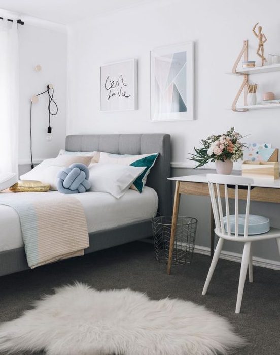 a stylish modern teen girl bedroom with a gallery wall, a grey upholstered bed, a small desk and touches of powder blue, blush and gold