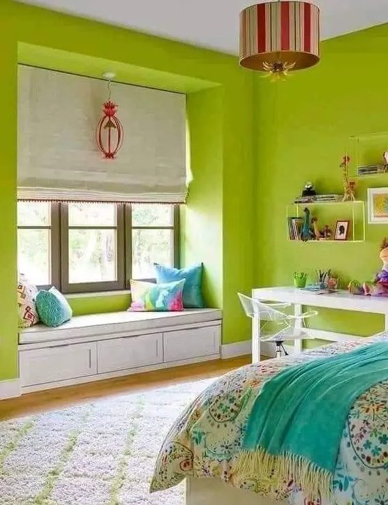 a super bright chartreuse bedroom with a bed and printed bedding, a desk and shelves, a windowsill bench with pillows